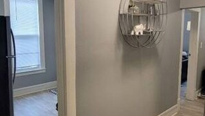 En hall med en modern lampa, en inbyggd hylla och en dörr som leder till ett annat rum.