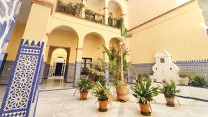 A courtyard with arches, potted plants, and a balcony. - Homey Seville. Duplex with Terrace in Santa Cruz, Sleeps 5, Parking Optional (Sevilla)