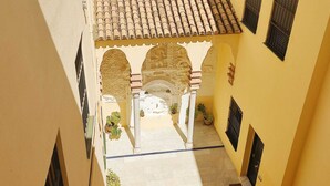 A narrow corridor with a tiled roof, arches, and potted plants. - Homey Seville. Duplex with Terrace in Santa Cruz, Sleeps 5, Parking Optional (Sevilla)