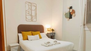 A neatly made bed with white and yellow bedding, a bedside table with a lamp, and a wall art piece above the bed. - Homey Seville. Duplex with Terrace in Santa Cruz, Sleeps 5, Parking Optional (Sevilla)
