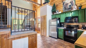 A spacious kitchen with green cabinets, a stainless steel refrigerator, a black oven, and a microwave. - Spacious Cabin in the Heart of Branson, near shows, shopping! (Branson)