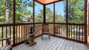 A wooden deck with a ceiling fan, a stone planter, and a wooden chair.