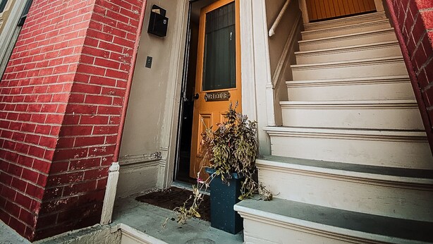 A red brick building with a white door and a staircase leading to the entrance.