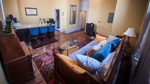 A spacious living area with a sofa, coffee table, and a dining area with chairs and a small kitchen.
