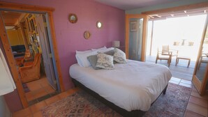 A bedroom with a bed, a patterned rug, and a view of the outside. - Groovy Desert Getaway w Pool, Fire pit, Stream/Wifi, Vinyl Records, Books, Art.. (Twentynine Palms)