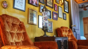 A room with plush velvet armchairs, a decorative lamp, and various framed artworks on the wall. - Groovy Desert Getaway w Pool, Fire pit, Stream/Wifi, Vinyl Records, Books, Art.. (Twentynine Palms)