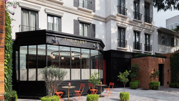 A hotel with a glass facade, outdoor seating area, and a brick wall. - The Alest Hotel (Mexico City)