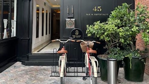 A building entrance with a black door marked "45" and a sign for "The Palace Bar & Restaurant". Two bicycles are parked in front. - The Alest Hotel (Mexico City)