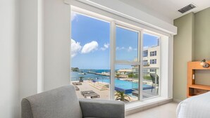 Ein Hotelzimmer mit großem Fenster und Blick auf einen Pool sowie Gebäude.