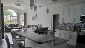 A modern kitchen with a central island, white cabinets, and stainless steel appliances. - 4 Bedroom Pool home with pond view in Sarasota, FL (Sarasota)
