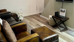 A living room with a brown leather sofa, a flat-screen TV, and a framed picture on the wall. - Timberline cabin close to Mt. Rainer and White Pass, WiFi, Netflix, AC (Packwood)