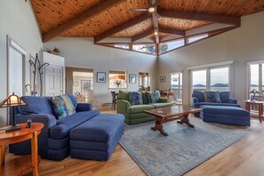 Relax in this spacious living area with a high ceiling, featuring a sofa, coffee table, and dining table.