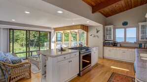 A spacious kitchen with a central island, white cabinetry, and a view of the outdoors. - Wings Cottage - Oceanfront! (Trenton)