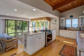 Enjoy cooking in this well-equipped kitchen with a central island, gas stove, and oven, offering a view of the surrounding greenery.