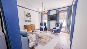 A living room with a sofa, two armchairs, a coffee table, a TV, and a wooden cabinet. - EAST 42 C - 1 Bedroom, 1 Block to King (Charleston)