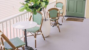 Une véranda avec des fauteuils en osier et une table, une plante en pot et une porte verte.