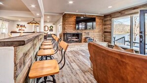 A modern kitchen with a central island, wooden bar stools, and a fireplace.