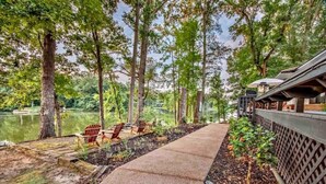 A pathway leading to outdoor seating with chairs and a view of a lake surrounded by trees.