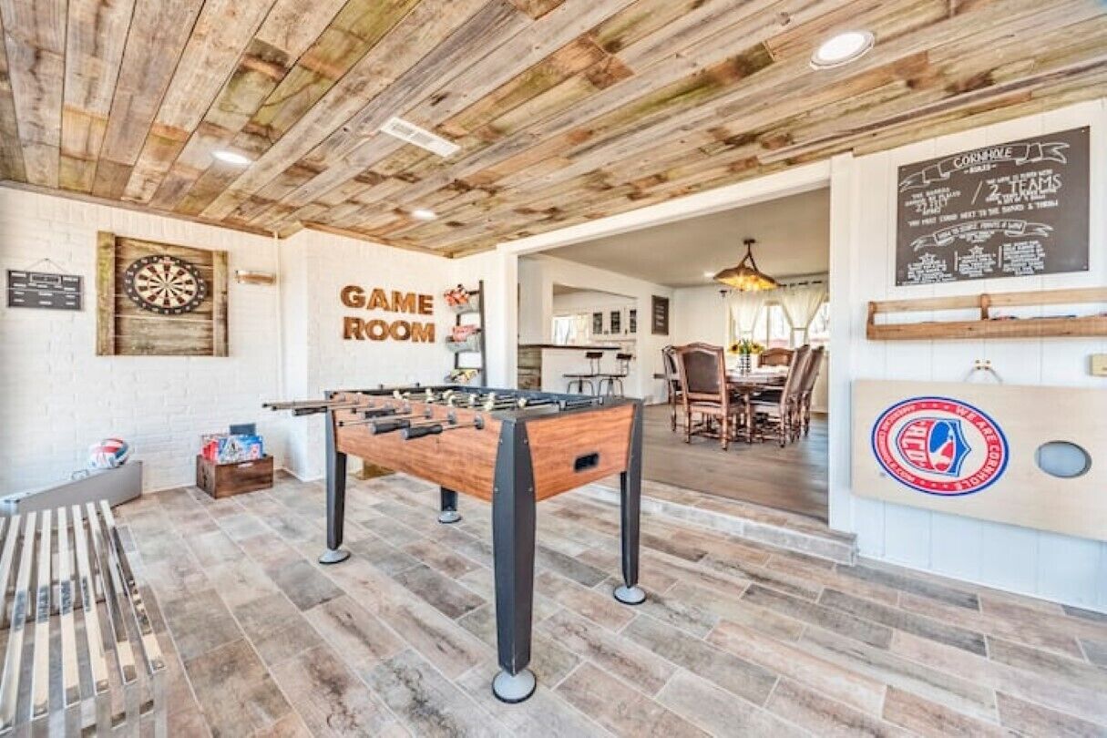 A game room with a foosball table, dartboard, and billiards table.