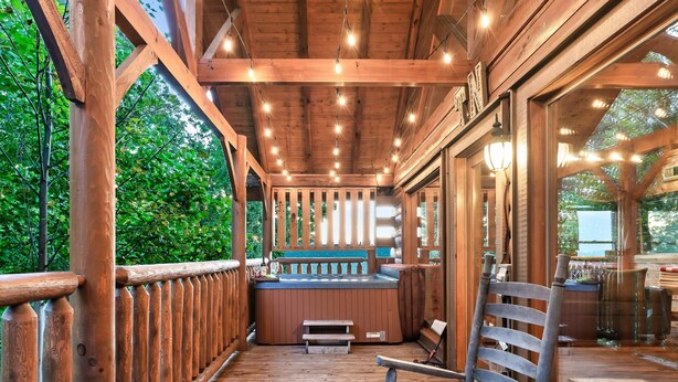Une terrasse en bois avec un jacuzzi, des rampes en bois et un banc.