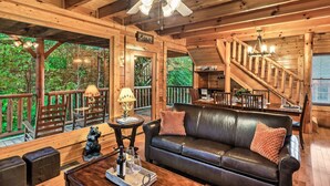 L’intérieur d’une cabane en bois est aménagé avec un canapé en cuir, une table à manger et un escalier menant à un niveau supérieur.