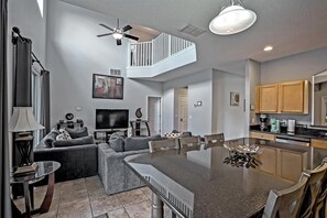 A modern living room with a large sectional sofa, a flat-screen TV, and a dining area with a large island.
