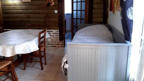 Een kamer met een ronde houten tafel, twee stoelen, een witte kast en een raam met uitzicht.