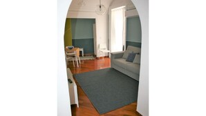 A living room with a grey rug, a white sofa, and a white chair. - Alley house historical center (Catania)