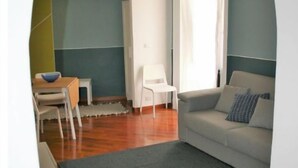 A living room with a grey rug, a white sofa, and a white chair.