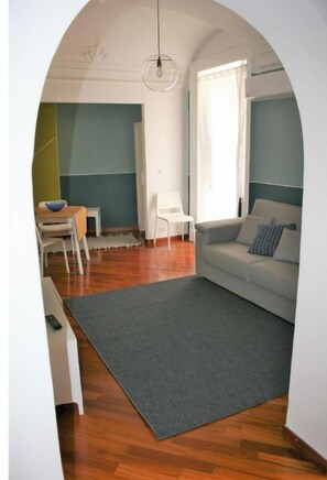 A living room with a grey rug, a white sofa, and a white chair.