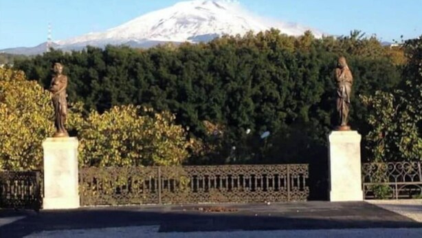 Two statues on pedestals with a snow-capped mountain in the background. - Alley house historical center (Catania)