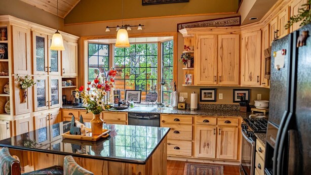 Cocina amplia con armarios de madera, una isla grande y vistas al exterior.