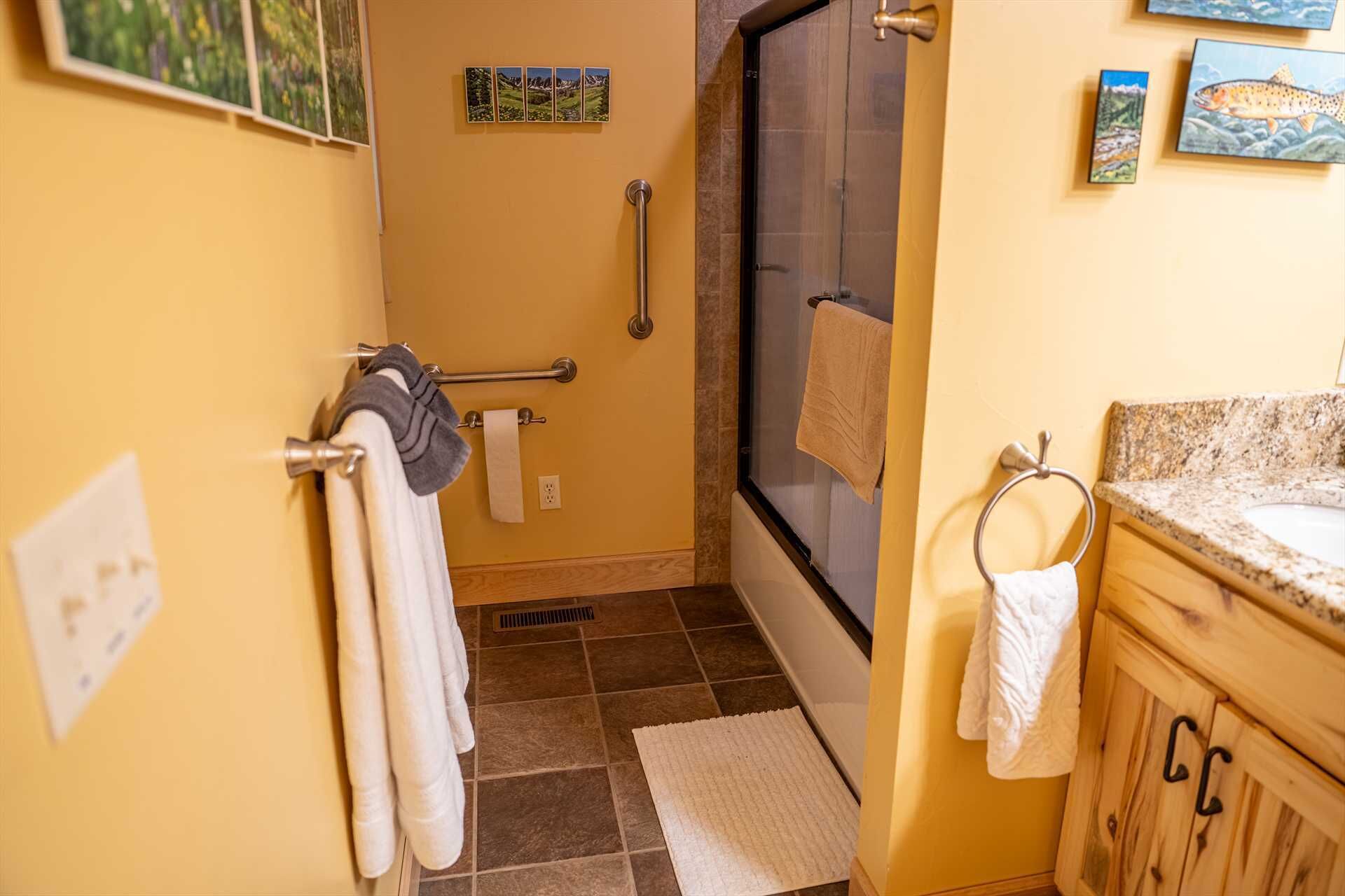 A bathroom with a shower, a sink, and a toilet. There are towels hanging on a rack and a towel on the floor.