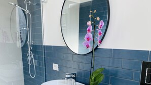 Een moderne badkamer met een wit wastafel, een ronde spiegel en een douchecabine.