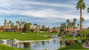 Un parcours de golf avec un étang, des palmiers et un bâtiment doté d’un toit rouge.