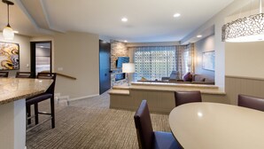 Une chambre d’hôtel moderne dotée d’un coin repas, d’un espace salon avec vue et d’un mur décoratif en pierre.
