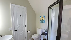 A bathroom with a toilet, sink, and shower area. - Spacious apartment, deep in the woods, with private entrance and deck (Cleveland)