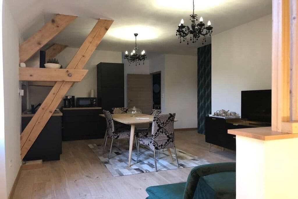 Eine moderne Küche mit Essbereich, einer Holztreppe und einem Kronleuchter.