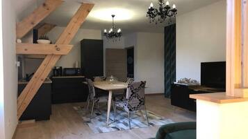 Eine moderne Küche mit Essbereich, einer Holztreppe und einem Kronleuchter.