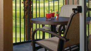 A balcony with a table and chairs, a palm tree, and a view of a golf course. - Marriott Shadow Ridge - Studio Villa with King bed (Palm Desert)