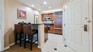 A kitchen with a central island, bar stools, a microwave, and a refrigerator. - SVS: MGM 2BR, Mtn View, Balcony & 3 Baths (Las Vegas)