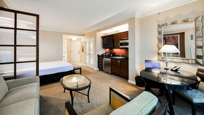 A hotel room with a bed, a seating area with a table and chairs, a kitchenette, and a bathroom. - SVS: MGM 2BR, Mtn View, Balcony & 3 Baths (Las Vegas)