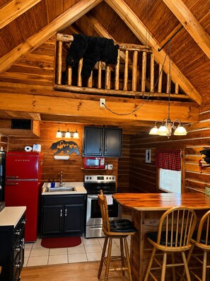 L’intérieur d’un chalet rustique comprend une cuisine, un coin repas et une mezzanine décorée sur le thème de l’ours.