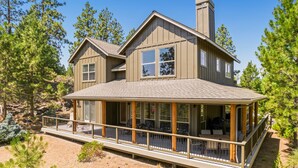 A two-story house with a covered porch, large windows, and a chimney. - BEAUTIFUL HOME OVERLOOKING THE RIVER-MINUTES TO IT ALL-UPDATED KITCHEN! (Bend)