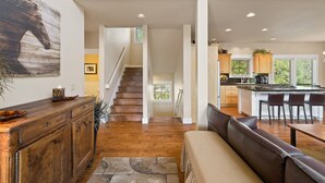 A modern kitchen with a central island, wooden cabinets, and a dining area with a bench. - BEAUTIFUL HOME OVERLOOKING THE RIVER-MINUTES TO IT ALL-UPDATED KITCHEN! (Bend)