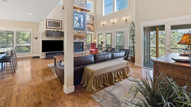 A spacious living room with a large sectional sofa, a fireplace, a flat-screen TV, and a dining area with a table and chairs. - BEAUTIFUL HOME OVERLOOKING THE RIVER-MINUTES TO IT ALL-UPDATED KITCHEN! (Bend)