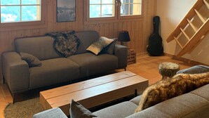 Un intérieur de chalet chaleureux avec un canapé, une table basse et un chien.