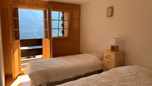 Une chambre avec deux lits, des murs en bois, une fenêtre et une table de chevet avec une lampe.