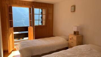 Une chambre avec deux lits, des murs en bois, une fenêtre et une table de chevet avec une lampe.