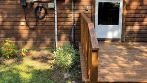 Une structure extérieure en bois, surmontée d’un toit en métal, avec une porte et des boîtiers électriques fixés au mur.